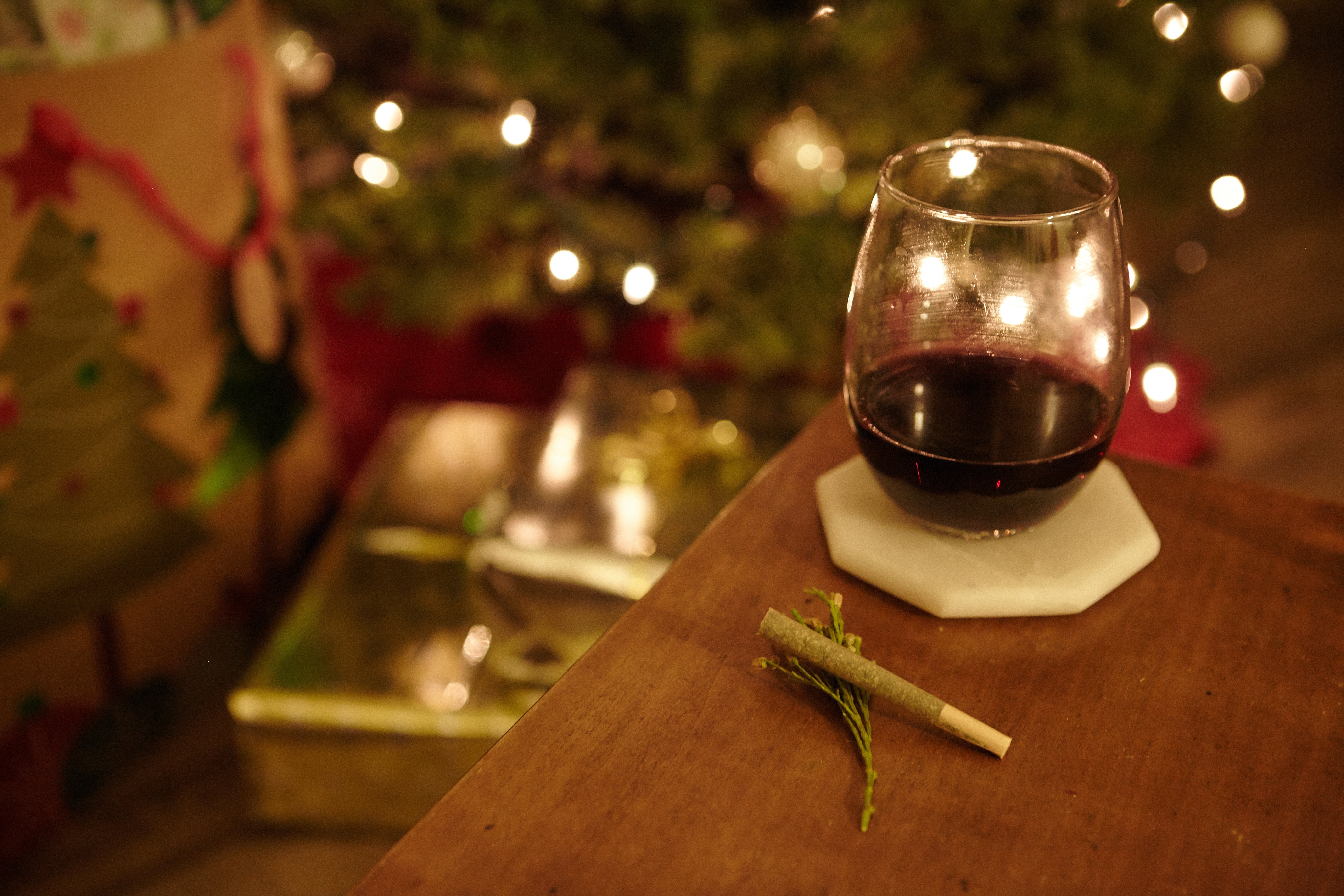 Nahaufnahme aus der Vogelperspektive von einem Marihuana-Blunt und einem Glas Cognac auf einem Tisch vor unscharfem Hintergrund.