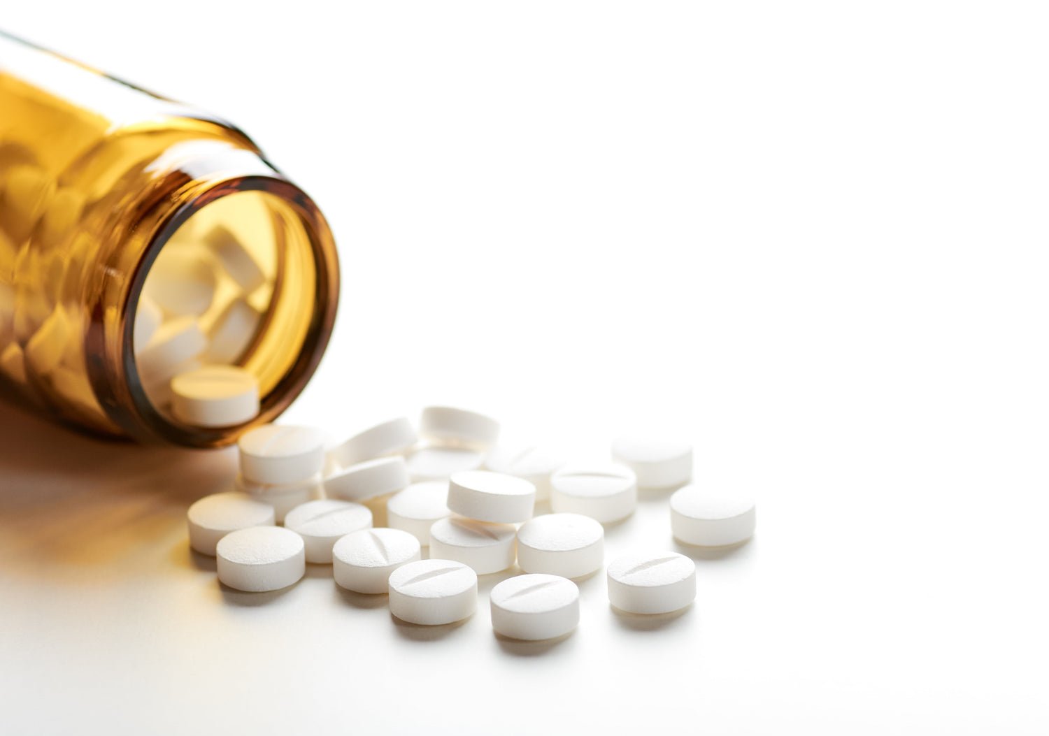 Stillleben mit einem Haufen weißer Pillen oder Tabletten und einer Glasflasche oder einem Glas.