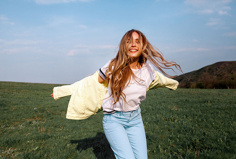 Frau in einer grünen Landschaft unter blauem Himmel