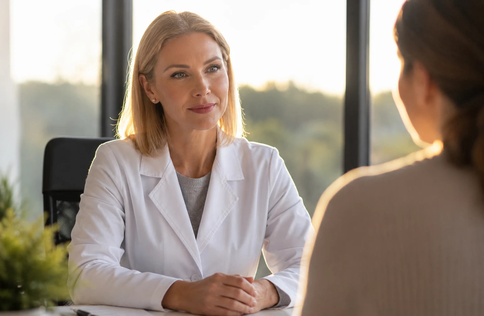 Eine Ärztin im Kittel unterhält sich mit einer Patientin in einer professionellen Umgebung.