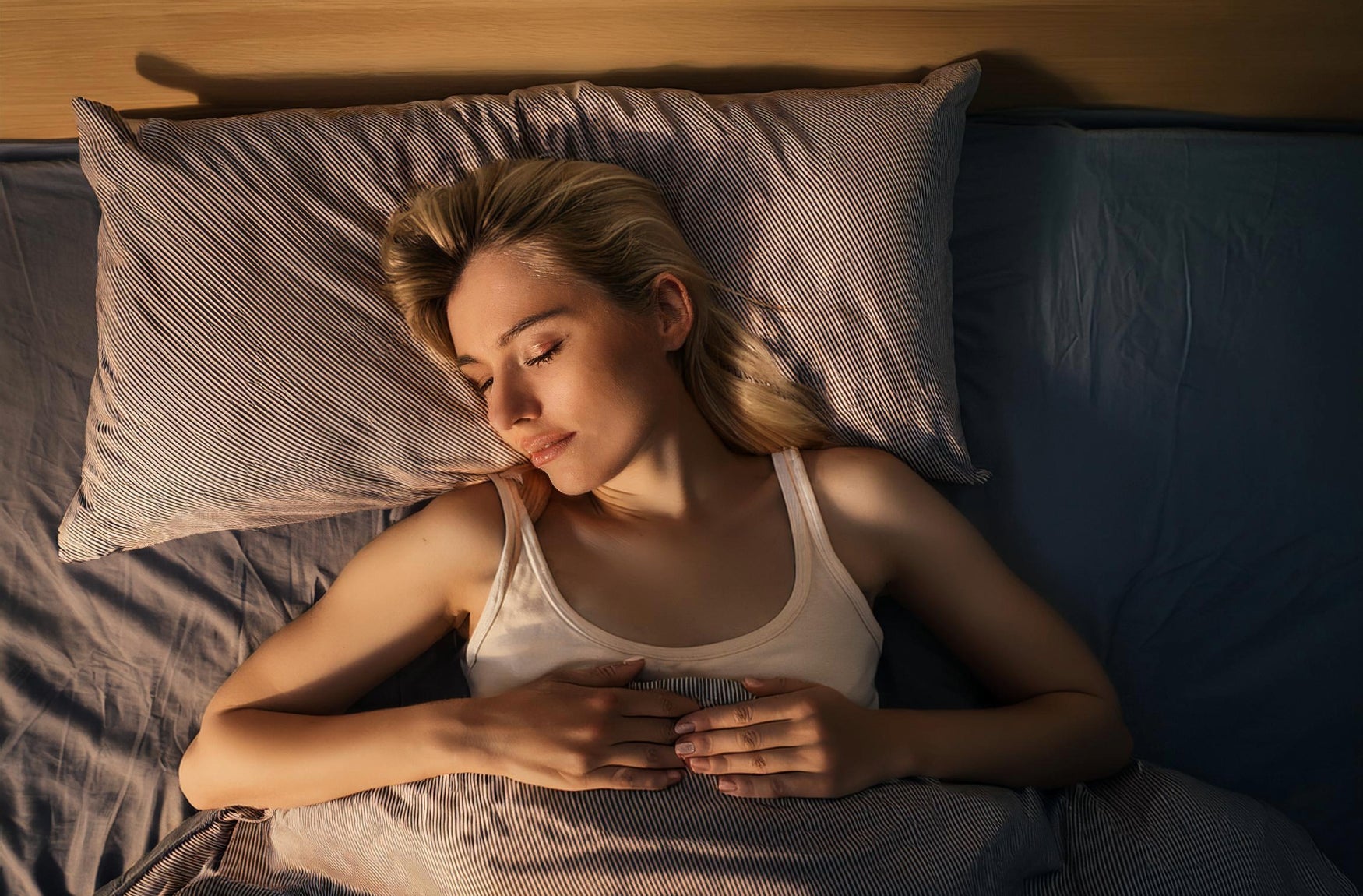 Eine Frau schläft im Bett mit geschlossenen Augen und wirkt entspannt und friedlich.